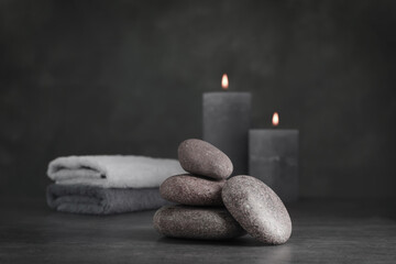 Obraz na płótnie Canvas Spa stones with candles and towel on grey table