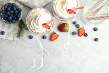 Tasty milk shakes with fresh berries on grey marble table, flat lay. Space for text