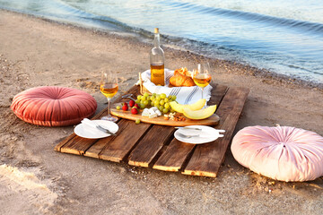 Fototapeta na wymiar Food for picnic and white wine served on wooden pallet near river