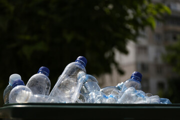 Many used plastic bottles in trash bin outdoors, closeup. Recycling problem