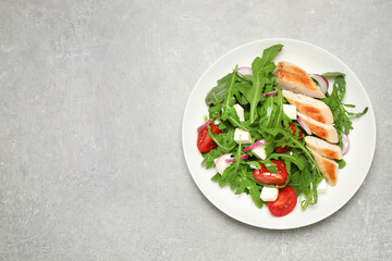 Delicious salad with meat, arugula and vegetables on grey table, top view. Space for text