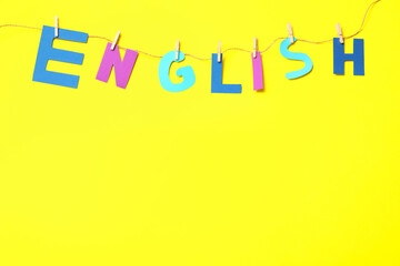 Thread with pinned word ENGLISH on yellow background, top view. Space for text