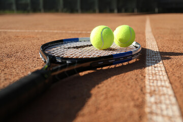 Tennis balls and racket on clay court, closeup