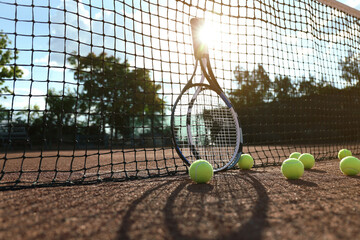 Tennis balls and rackets near net on clay court