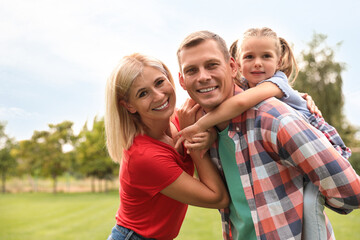 Fototapeta premium Cute little girl having fun with her parents in park on summer day