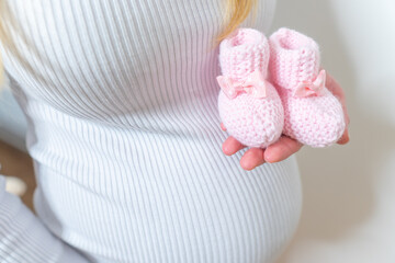 Small shoes for the unborn baby in the belly of pregnant woman