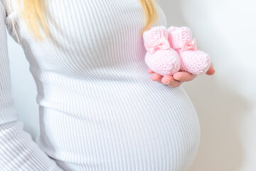 Small shoes for the unborn baby in the belly of pregnant woman