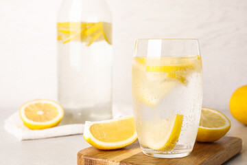 Fototapeta premium Soda water with lemon slices on light table. Space for text