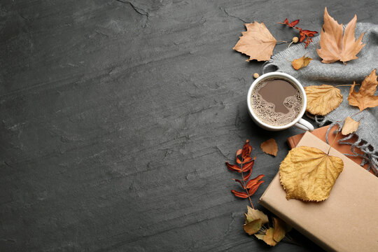Flat lay composition with cup of hot drink and autumn leaves on black table, space for text. Cozy atmosphere