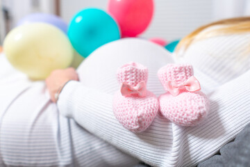 Beautiful pregnant woman is smoothing her tummy and smiling during baby shower