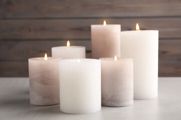 Fototapeta na wymiar Set of different burning candles on light grey stone table