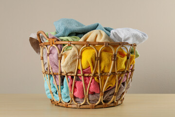 Wicker laundry basket with towels on wooden table