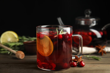Fototapeta premium Tasty hot cranberry tea with rosemary and lemon on wooden table