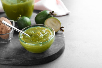 Feijoa jam in glass bowl on grey table. Space for text
