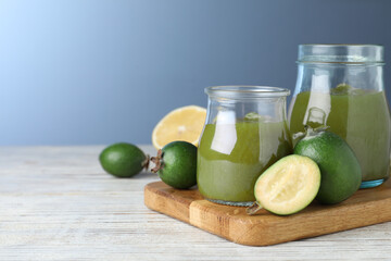 Feijoa jam and fresh fruits on white wooden table against light blue background. Space for text