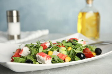 Tasty crab stick salad served on grey marble table, closeup