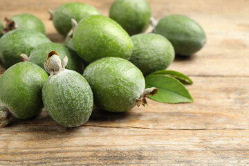 Fresh green feijoa fruits on wooden table, closeup. Space for text