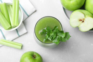 Flat lay composition with glass of fresh celery juice on light marble table