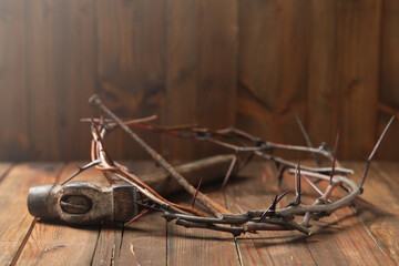 Crown of thorns, hammer and nail on wooden table, space for text. Easter attributes