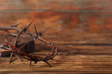 Crown of thorns and hammer on wooden table, closeup with space for text. Easter attributes