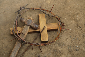 Crown of thorns, wooden cross and hammer with nail on ground, above view. Easter attributes