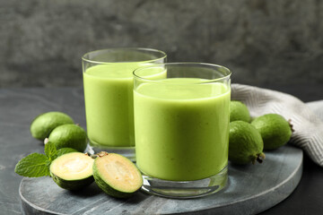 Fresh feijoa smoothie and fresh fruits on grey board, closeup
