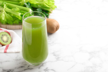 Glass with fresh celery juice on white marble table, closeup. Space for text