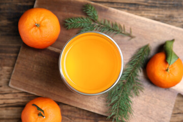Delicious tangerine jelly and fir branches on wooden table, flat lay