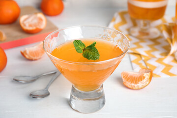 Delicious tangerine jelly in glass on white wooden table, closeup