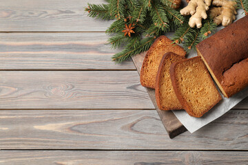 Delicious gingerbread cake, ingredients and fir branches on wooden table, flat lay. Space for text