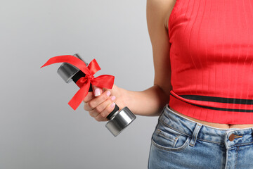 Woman with dumbbell as symbol of girl power on light grey background, closeup. 8 March concept