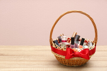 Fototapeta na wymiar Wicker gift basket with cosmetic products on wooden table. Space for text