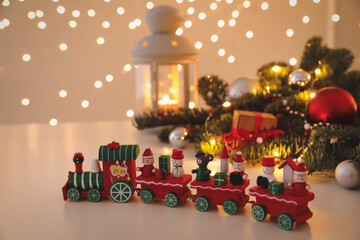 Toy train and Christmas decor on table against blurred lights
