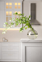Decorative vase with branch on table in kitchen