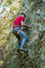 Young handsome sportsman climbing up a rock cliff