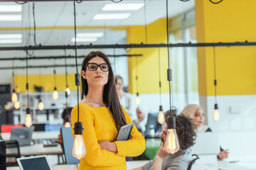 Female boss, manager executive posing in a modern startup office while being surrounded by her coworkers, team.