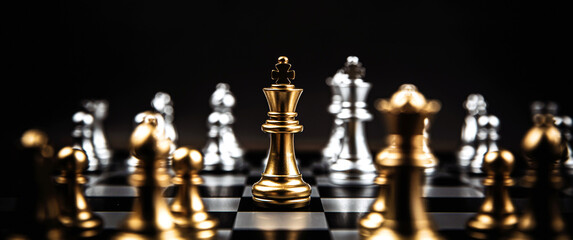 Close up king chess standing in the middle on chess board with silver chess concepts of business team and leadership strategy and organization management.