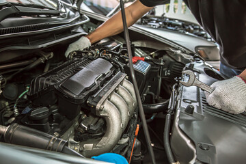 Close-up hands of auto mechanic are using the wrench to repair and maintenance auto engine is problems at car repair shop. Concepts of car care check and fixed and services insurance.