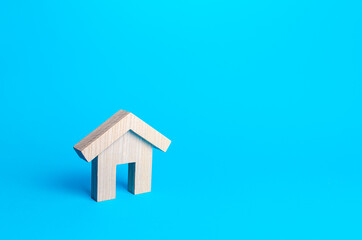 Obraz na płótnie Canvas Wooden figurine of a residential building on a blue background. Minimalism. Mortgage loan. Affordable housing. Rent or sale real estate. Construction industry. Realtor services. Copy space.
