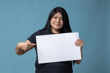 Your text here. Mexican Latin woman holding empty blank board. Studio portrait with blue background.