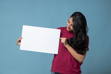 Your text here. Mexican Latin woman holding empty blank board. Studio portrait with blue background.