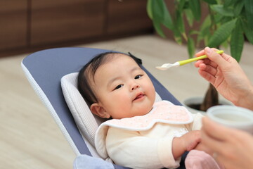 リビングで離乳食を食べさせてもらう赤ちゃん