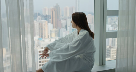 Woman with bathrobe and open the curtain to enjoy the view from window at morning