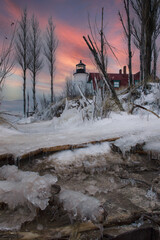Lighthouse ice and snow under colorful sunset 