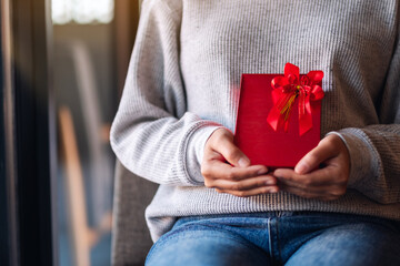 Closeup image of a woman holding a red present box