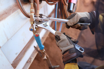 Safety workplaces worker waring heavy duty a safety hand glove while using spanners adjustable wrench tension tightening oxy handpiece prior used  on site 