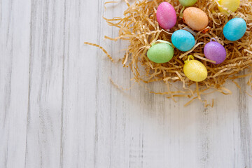 Colorful Easter eggs in a nest, on a light wooden background.top view. Copy space.  