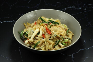 Fried and stirred spicy tofu sheet with mushroom, chilly and spring onion serving on the plate. 