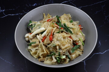 Fried and stirred spicy tofu sheet with mushroom, chilly and spring onion serving on the plate. 