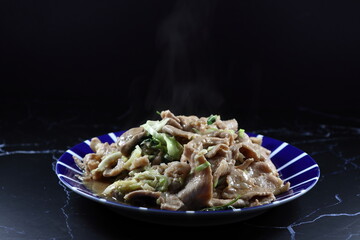 Fried and stirred sliced pork with traditional sauce and pepper serving on the plate. 